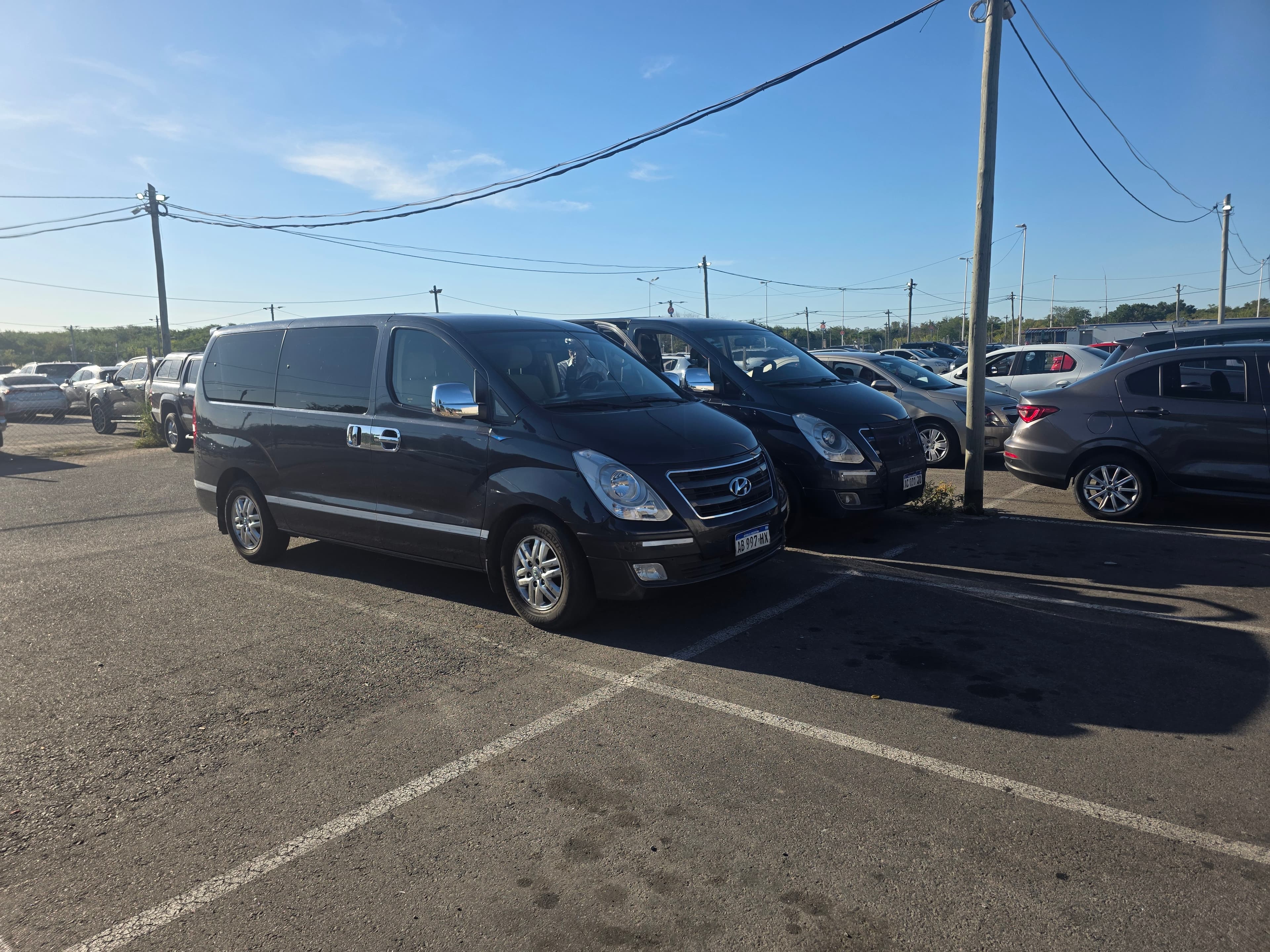 Dos furgonetas Hyundai negras estacionadas en un aparcamiento exterior bajo un cielo azul despejado.
